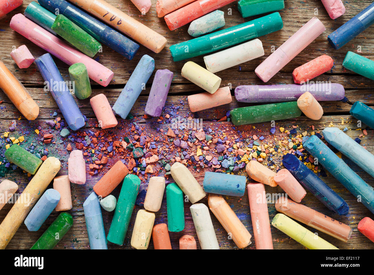 Sammlung von Regenbogen farbige Pastellstiften mit Pigment Staub auf alten Schreibtisch. Stockfoto