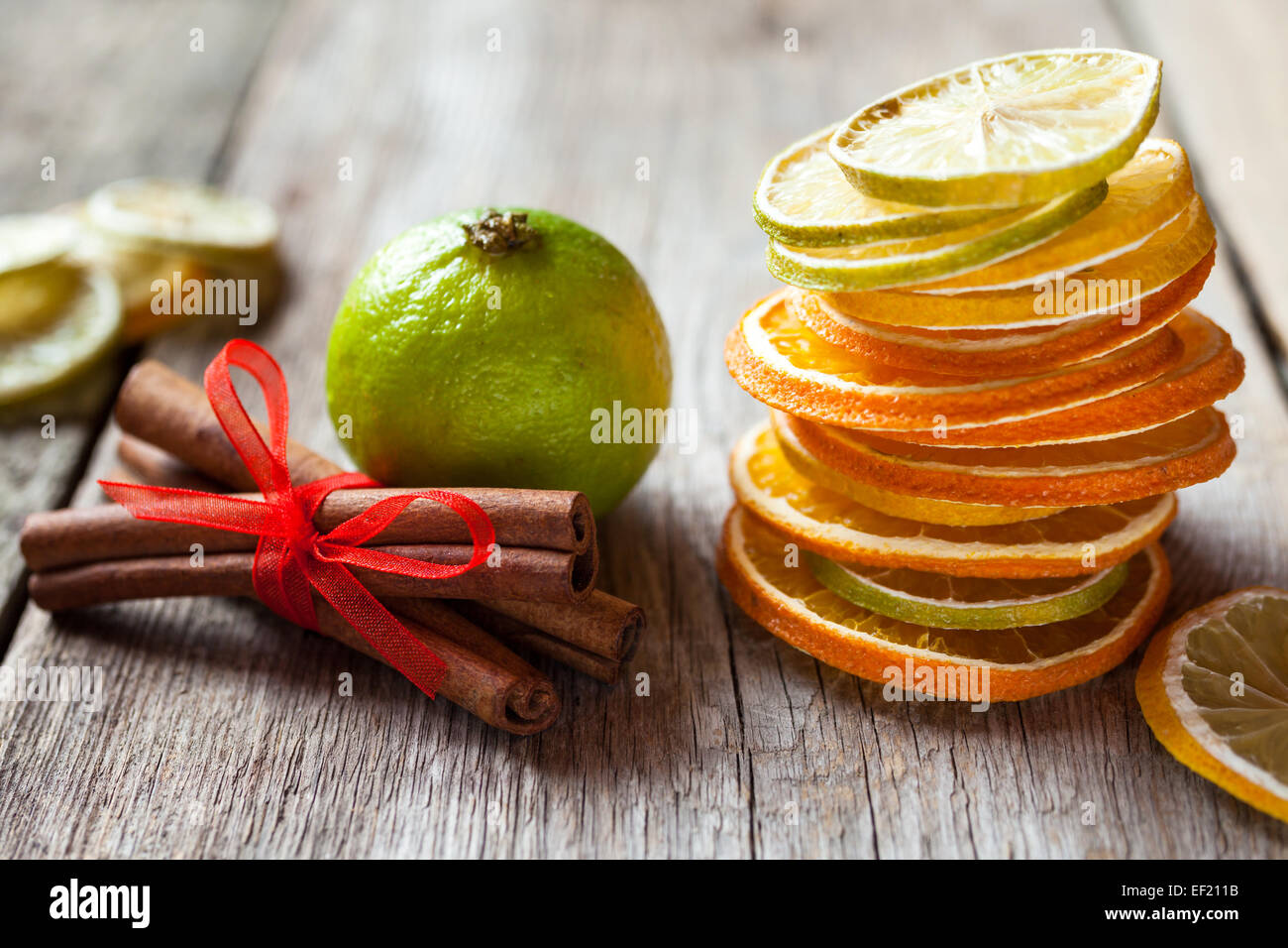 Stapel von getrockneten Orangen und Zitronenscheiben, Kalk und Zimtstangen auf alten Holztisch. Stockfoto