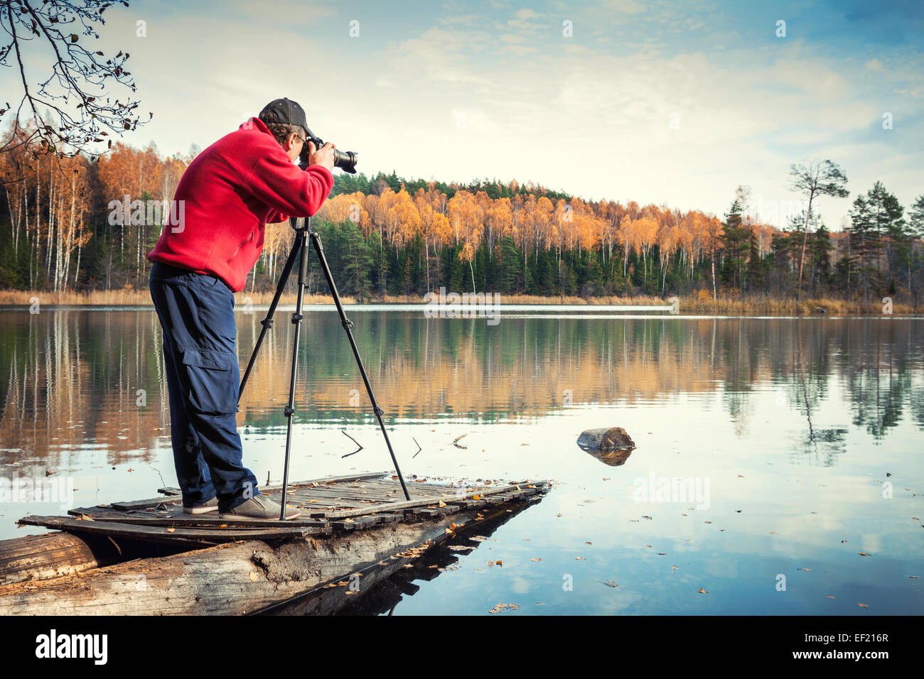 Mann-Fotograf mit Kamera auf einem Pier, Herbstlandschaft Stockfoto