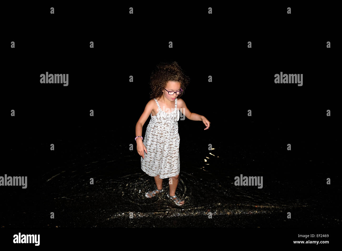 Sechs Jahre altes Mädchen Paddeln im Meer in der Nacht. Stockfoto