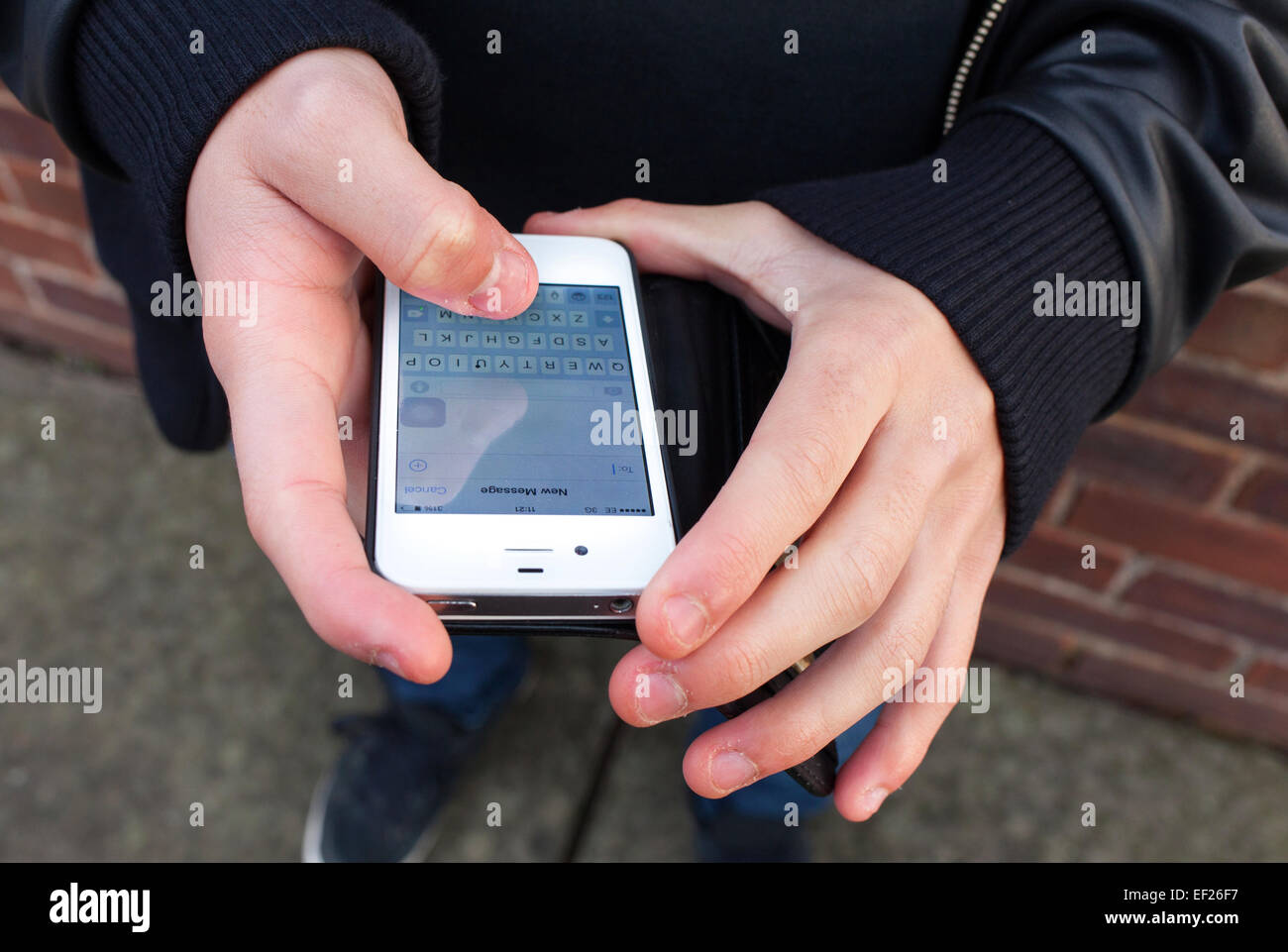 Ein Teenager mit einem iPhone, dass eine SMS in Großbritannien. Stockfoto