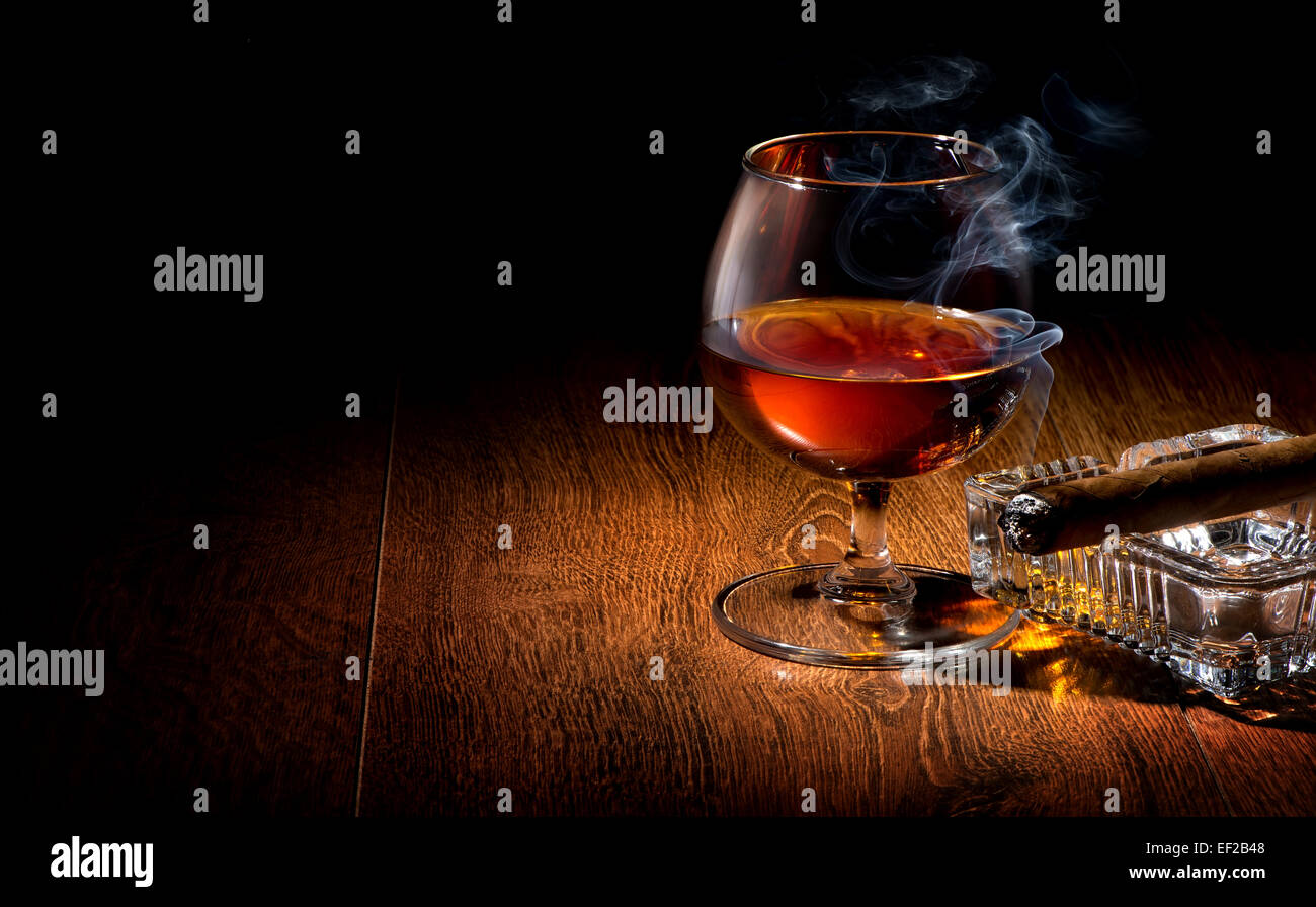 Cognac und Zigarren auf Aschenbecher auf einem Holztisch Stockfoto