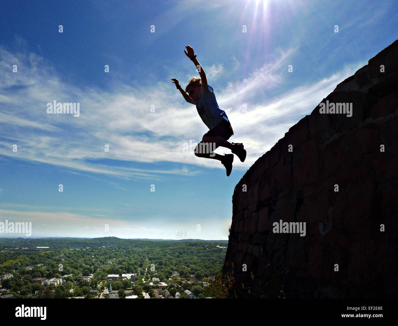 Kind von einer Klippe springen sah aus wie er frei fallend über eine Stadt ist Stockfoto