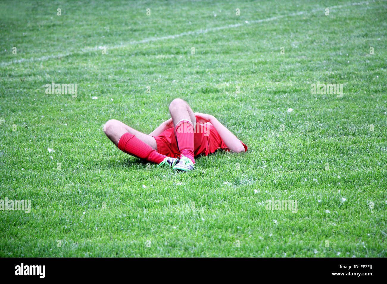 Verletzten Fußball- oder Fußball-Spieler auf dem Boden liegend Stockfoto