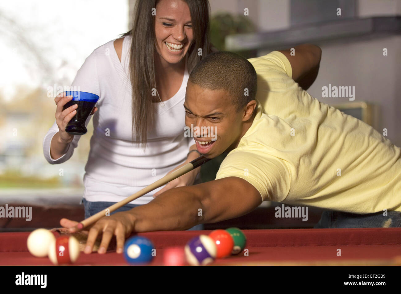 Mann, Billard spielen, während Freundin ihn ablenkt Stockfoto