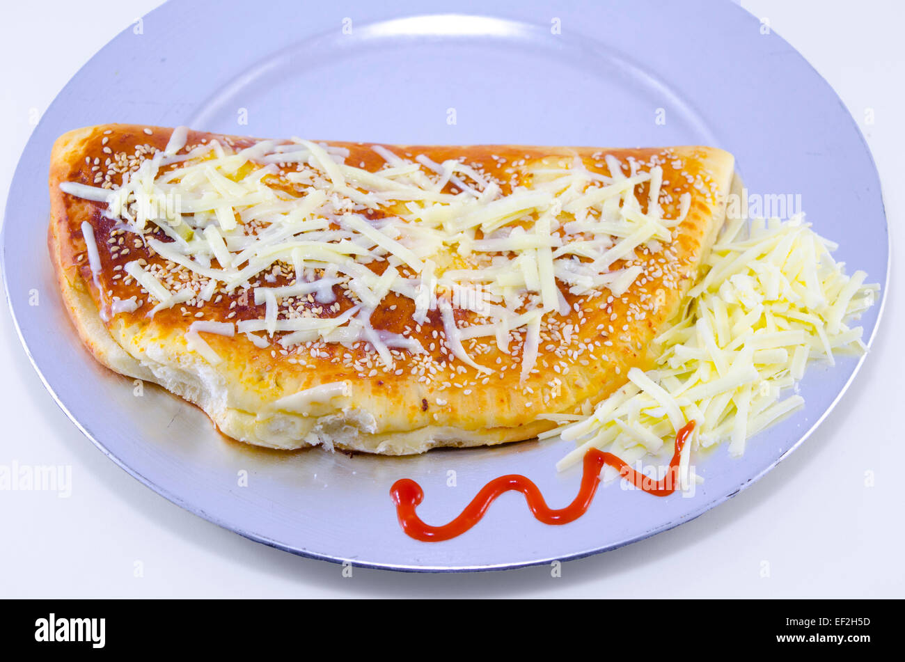 Home gebackene Piroge Pizza auf einem Teller dekoriert mit geriebenem Käse und ketchup Stockfoto