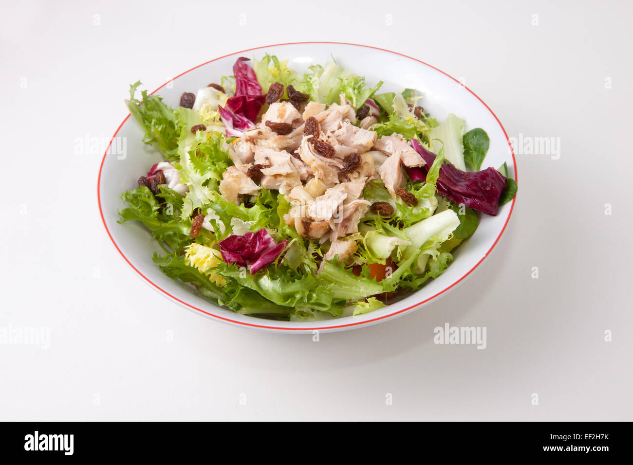 Hähnchen-Salat mit Tomaten und Rosinen in eine Schüssel weiß. Isoliert auf weißem Hintergrund Stockfoto