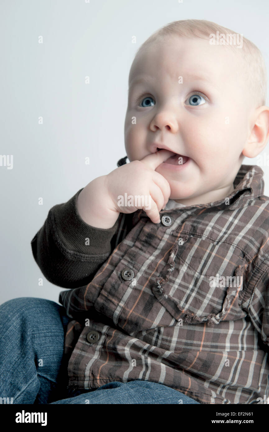Neun Monate altes Baby junge Lächeln, Hand im Mund Stockfoto