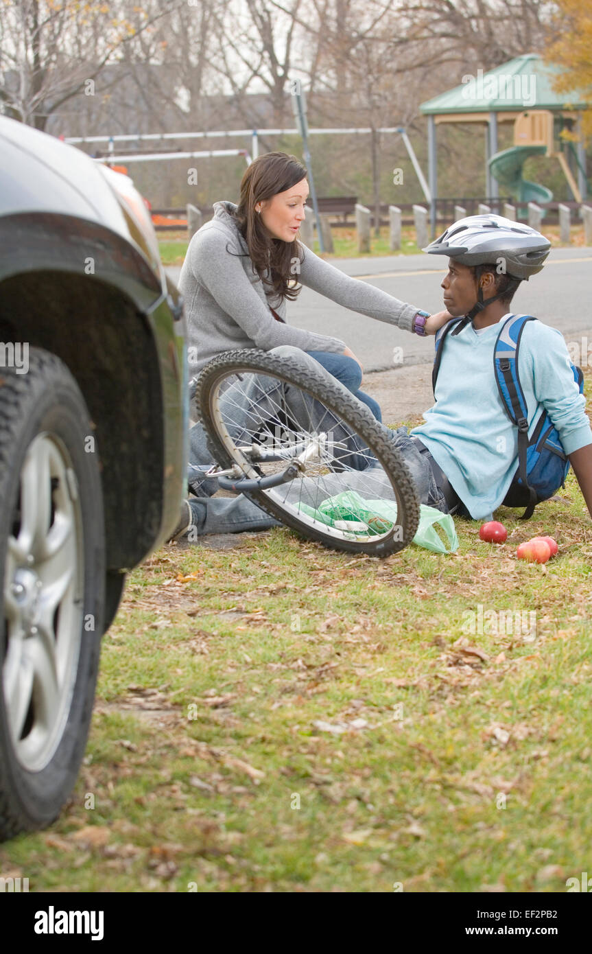 Frau im Gespräch mit Radsportler, nachdem er von einem Auto angefahren wurde Stockfoto