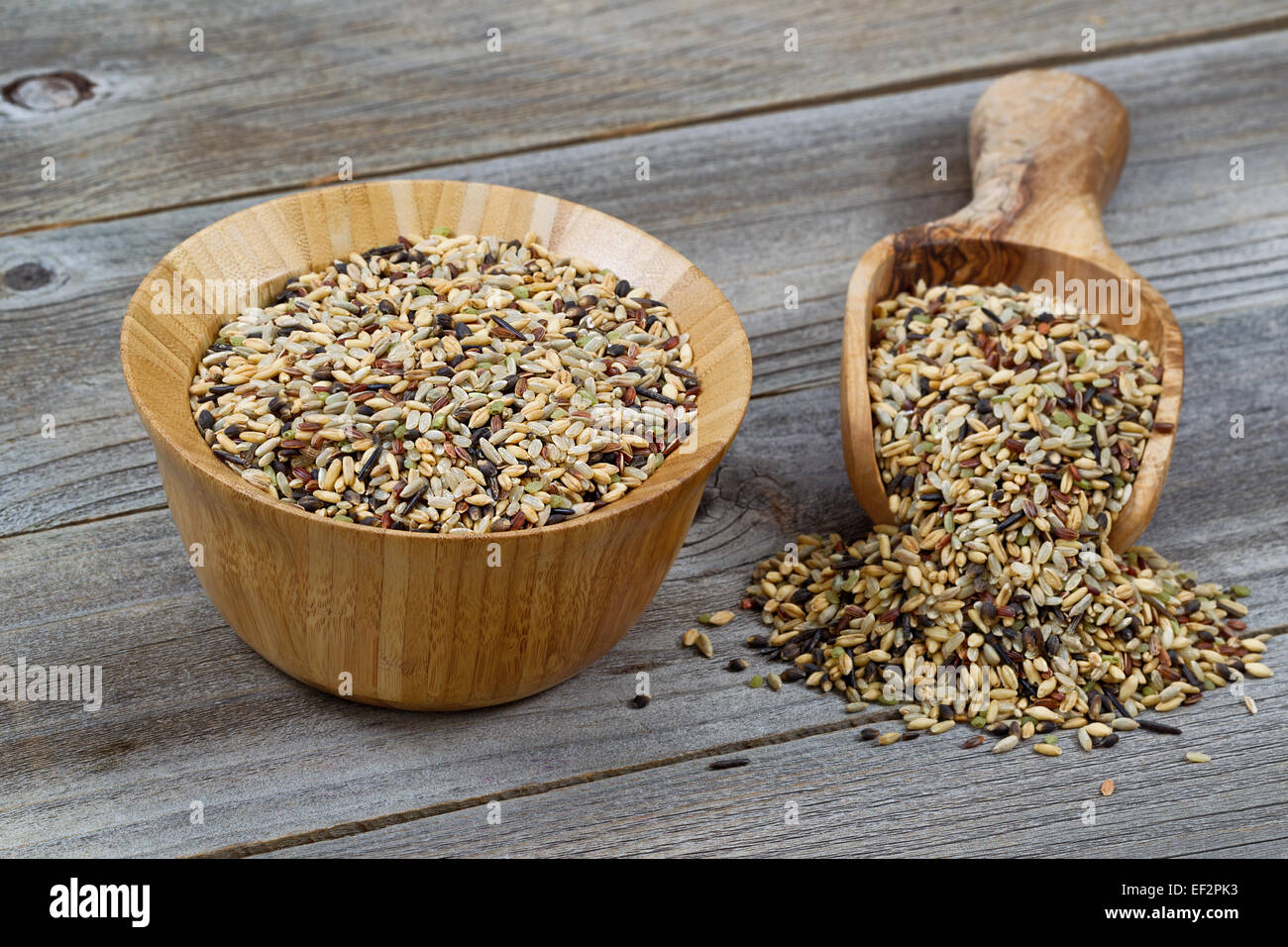 Schließen Sie nach vorne Schuss einer Holzschale und Schaufel gefüllt mit Vollkorn-Reis Verschütten auf rustikalen Holz Stockfoto