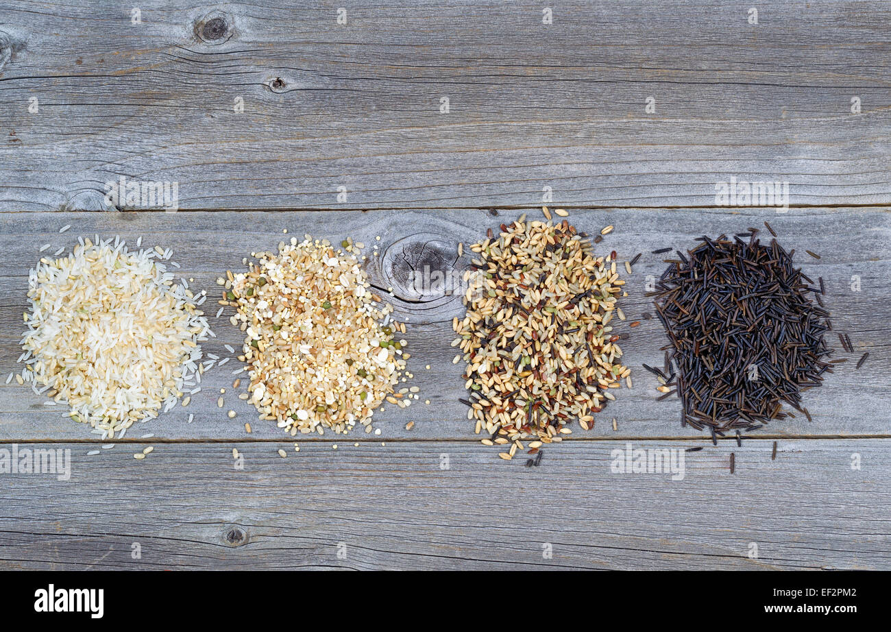 Draufsicht der verschiedenen Reis Typen jeweils innerhalb einer einzelnen Haufen auf rustikalen Holz Stockfoto