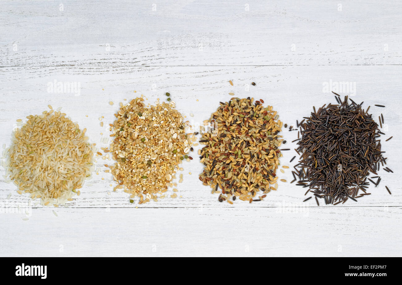 Draufsicht der verschiedenen Reis Typen jeweils innerhalb einer einzelnen Haufen auf weißem Holz Stockfoto