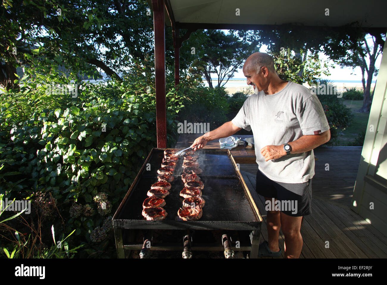 Host-Rob Jahnke Vorbereitung einen Grill in Wilsons Meadowbank Homestead Lodge in Awaroa Bucht, Nelson, Neuseeland Stockfoto