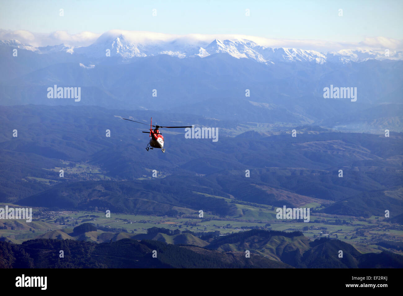 Ein Hubschrauber fliegt über bergiges Land in Richtung Nelson mit dem Schnee begrenzt Mount Arthur Bereich in der Ferne Stockfoto