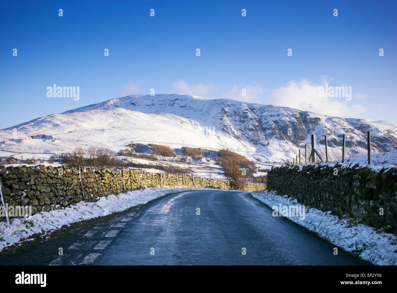 Straße auf der Westseite des Lakelandpoeten-Gebirges im Winterschnee. Seenplatte, Cumbria, England. Stockfoto