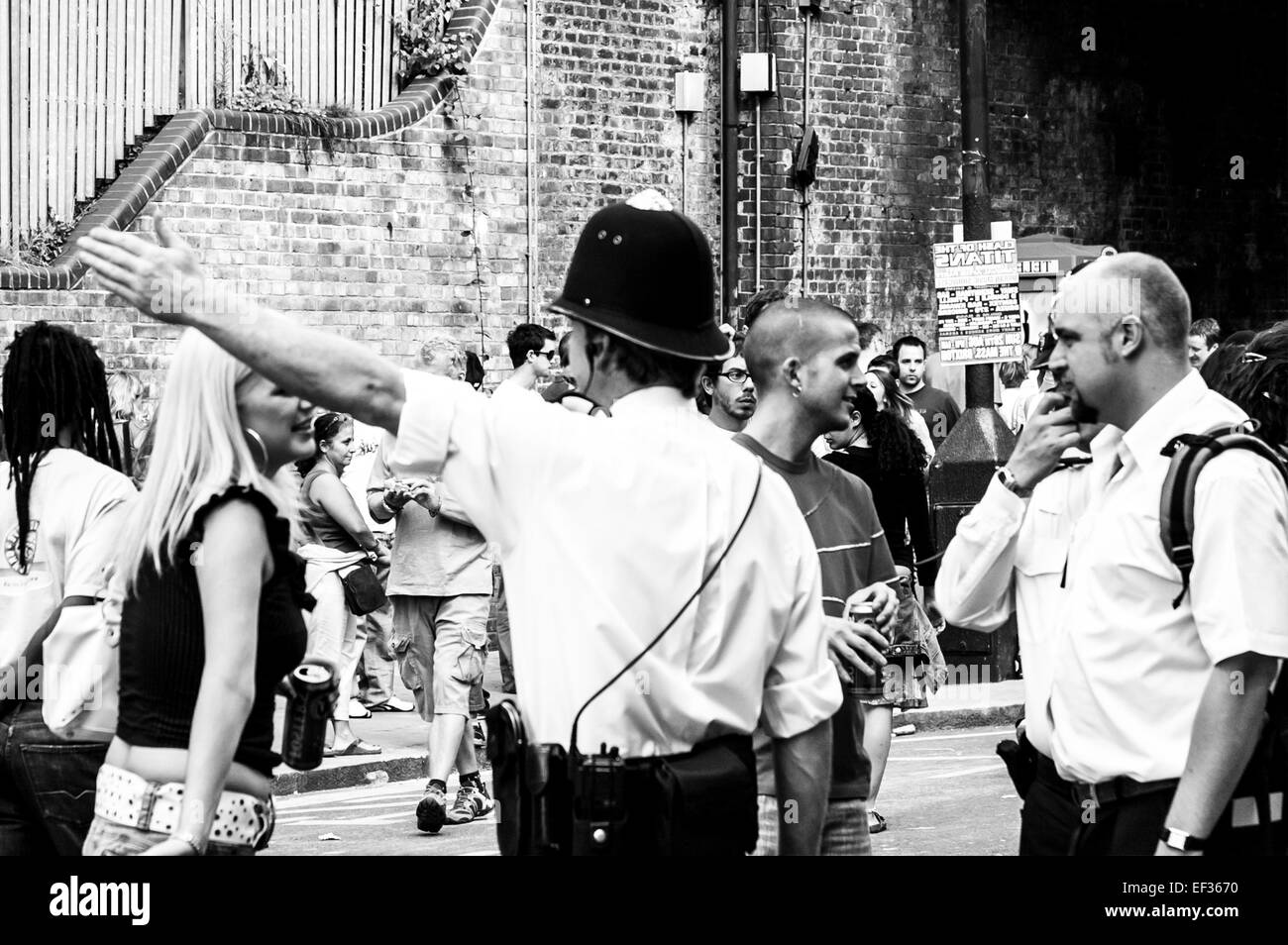 LONDON, UK - 28. August 2005: bei Notting Hill Carnival Polizist mit seinem Arm oben zeigt Richtung, Mitglied der Öffentlichkeit. Stockfoto