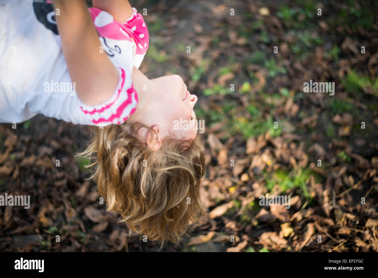 sonnendurchflutetes lächelndes Kind kopfüber hängend Stockfoto