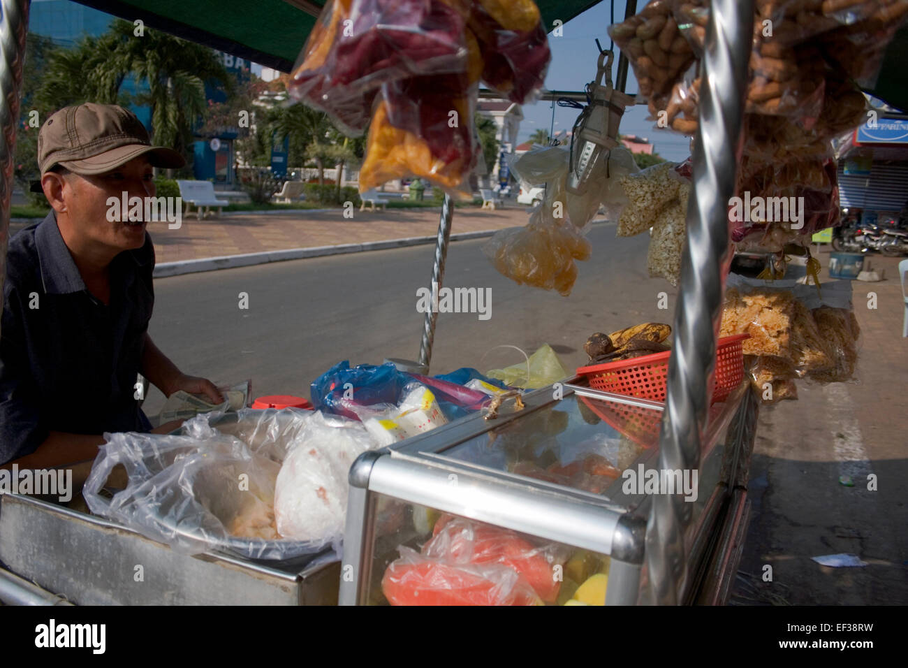 Ein Mann ist frisches Obst von einem mobilen Lebensmittel Karren auf eine Stadt Straße in Kampong Cham, Kambodscha tätig. Stockfoto