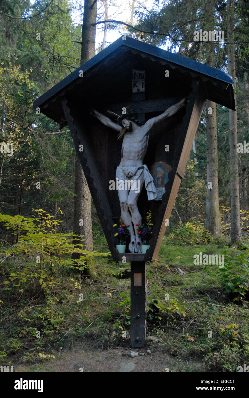 „Wegkreuz mit Marterl“ von Rinn ist eine historische religiöse Darstellung mit einem Wegeskreuz mit einem kleinen Schrein, das traditionelle deutsche Kunst widerspiegelt. Stockfoto
