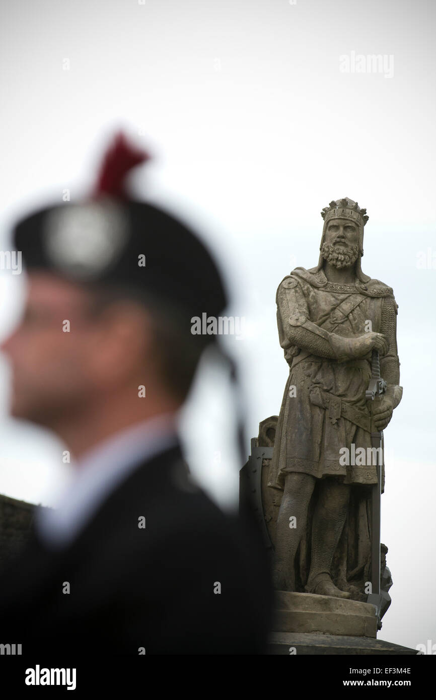 Ein Mann, gekleidet in traditionellen schottischen Outfit wird durch den Staat von Robert the Bruce vor Beginn der Pipefest, Stirling umrahmt. Stockfoto