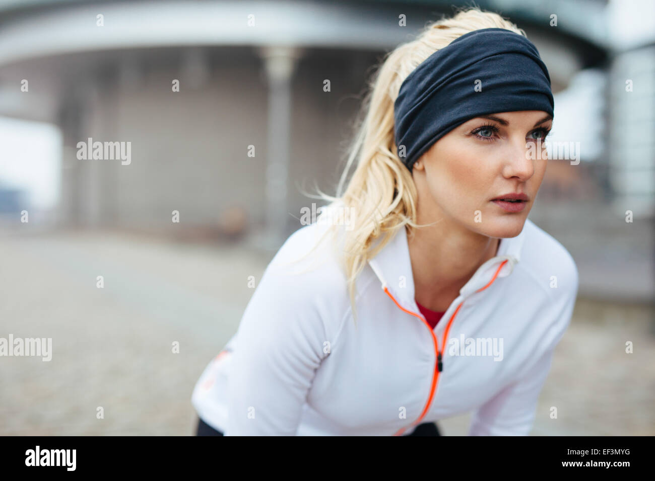 Porträt der jungen Sportlerin beugte sich über und wegsehen. Motiviert und konzentriert sich sportliche Frau vor einem Lauf. Stockfoto
