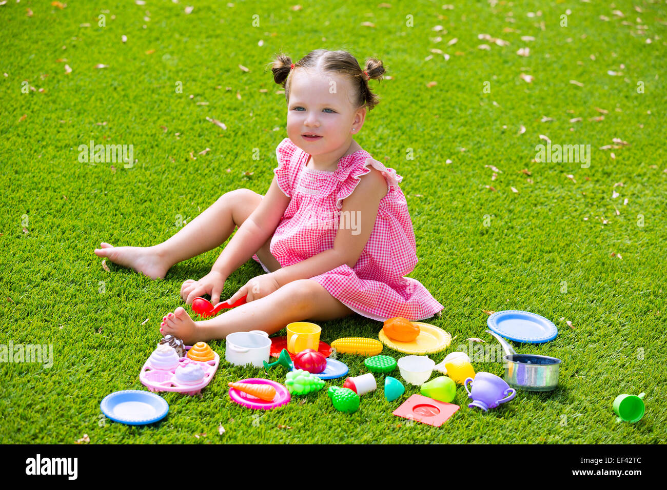 Kleinkind Kind Mädchen spielen mit Lebensmittel-Spielzeug im grünen Rasen Rasen Garten Stockfoto