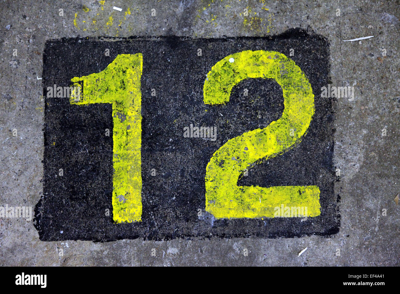 Draufsicht auf die Zahl 12 in eine Schablone Stil in gelber Farbe auf den Boden gemalt. Es ist in ein schwarzes Quadrat Stockfoto