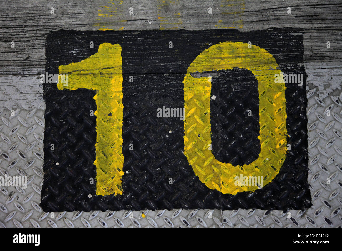 Draufsicht auf die Zahl 10 in eine Schablone Stil in gelber Farbe auf den Boden gemalt. Es ist in ein schwarzes Quadrat Stockfoto