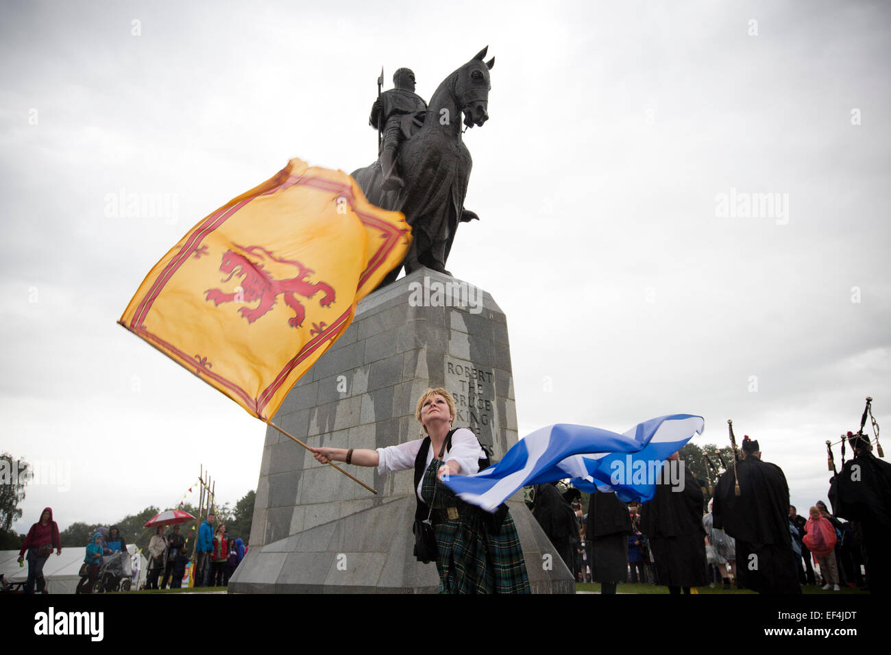 Eine Frau mit zwei schottischen Fahnen tanzen vor der Statue zu Robert the Bruce bei Veranstaltungen im Rahmen von Bannockburn Live, Schottland. Stockfoto