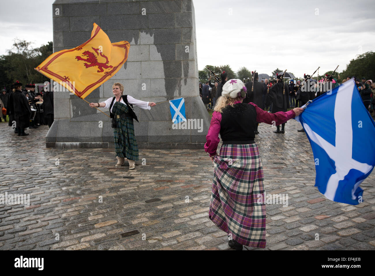 Eine Frau mit zwei schottischen Fahnen tanzen vor der Statue zu Robert the Bruce bei Veranstaltungen im Rahmen von Bannockburn Live, Schottland. Stockfoto