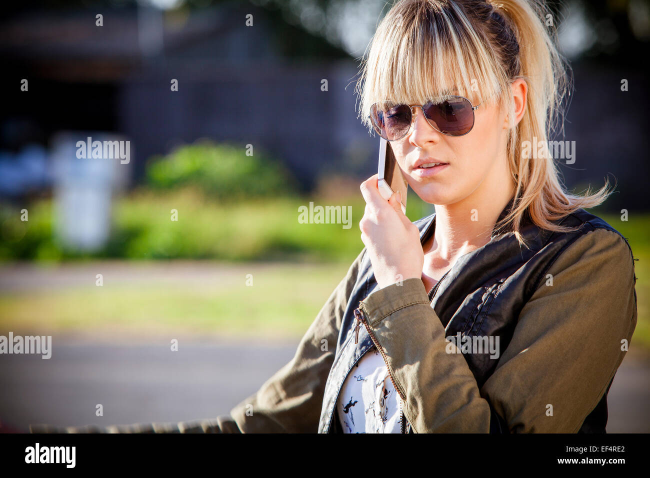 Junge Frau mit Sonnenbrille mit Handy Stockfoto
