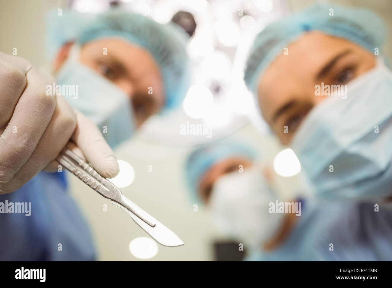 Junge Chirurgen, Blick nach unten in die Kamera halten Skalpell Stockfoto