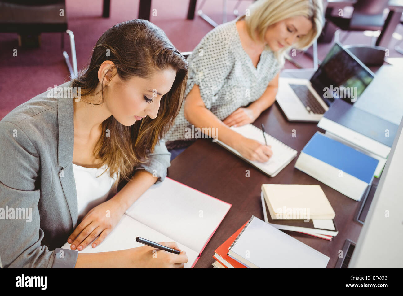 Reift Weibchen Studenten schreiben von Notizen am Schreibtisch Stockfoto