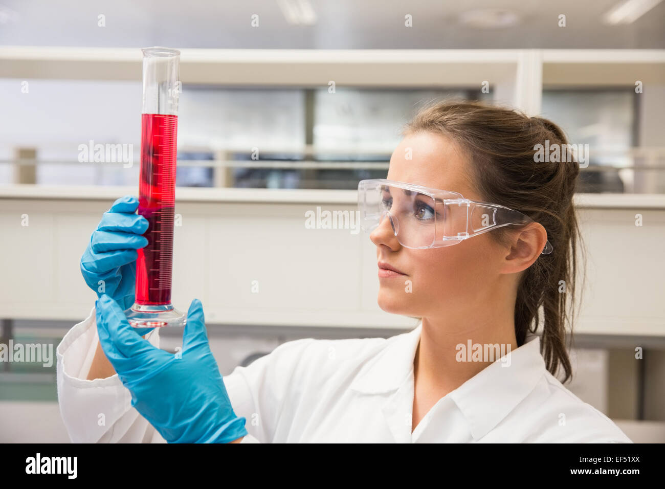 Junger Apotheker hält Becher mit roter Flüssigkeit Stockfoto