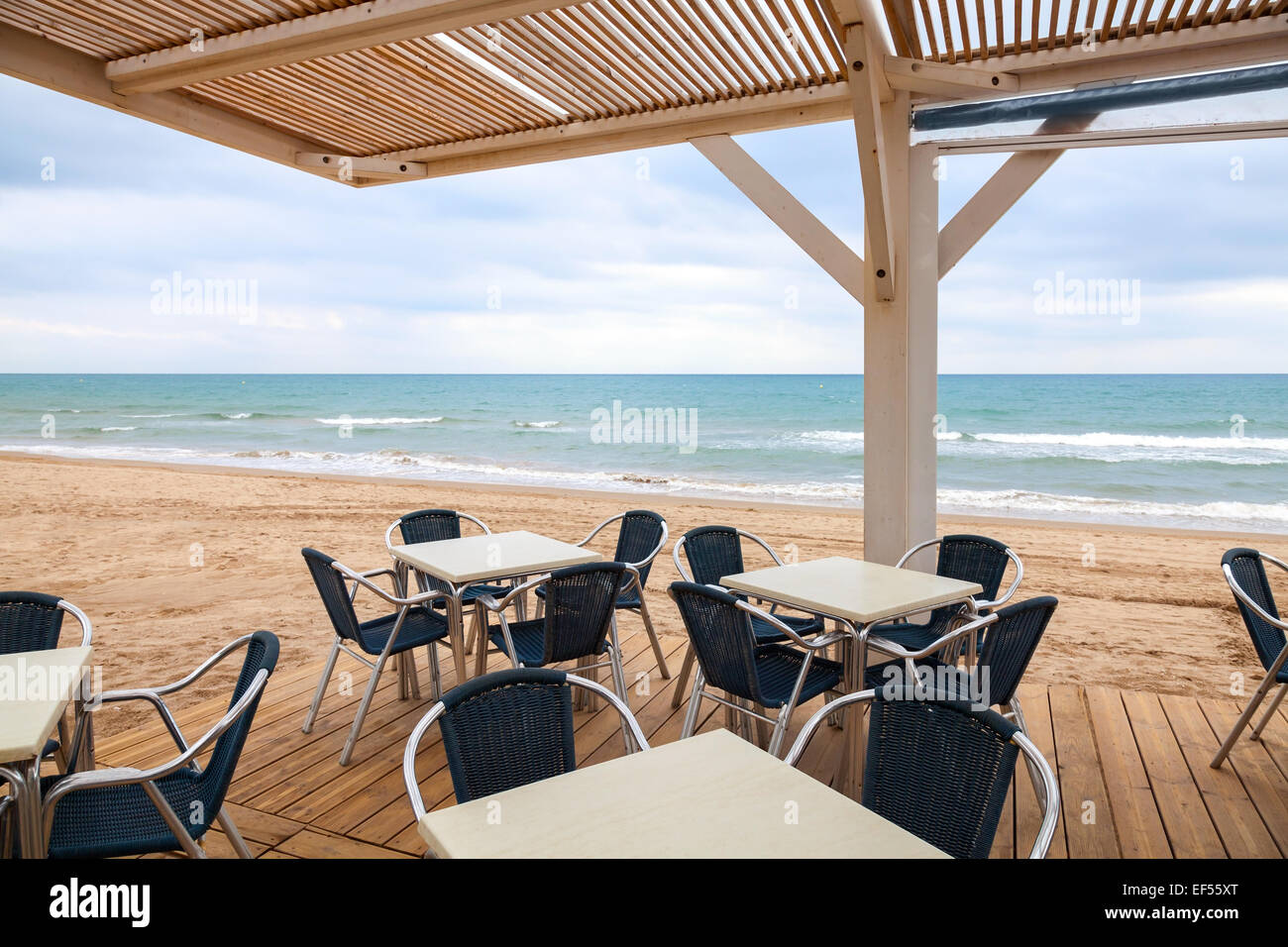 Freifläche am Meer Bar Interieur mit Holzboden, Dach und Metall Sessel am Sandstrand Stockfoto