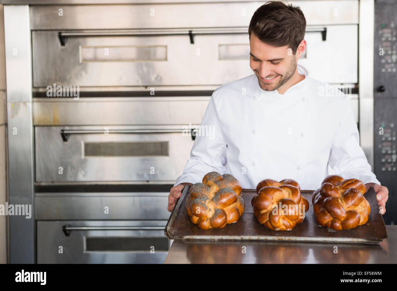 Glücklich Baker zeigt Tablett mit frischen Brötchen Stockfoto
