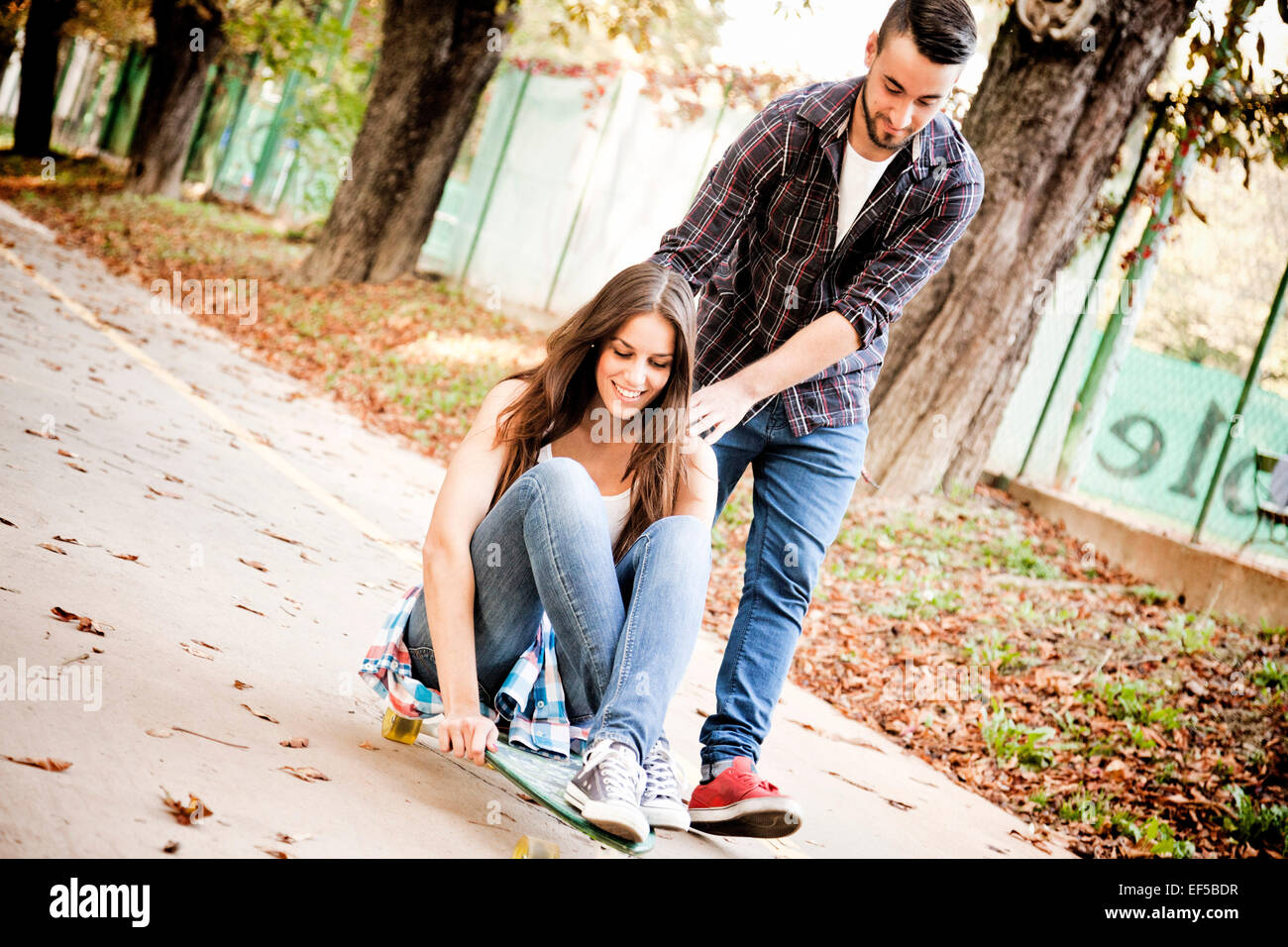 Junge Frau skateboarding, unterstützt ihr Mann Stockfoto