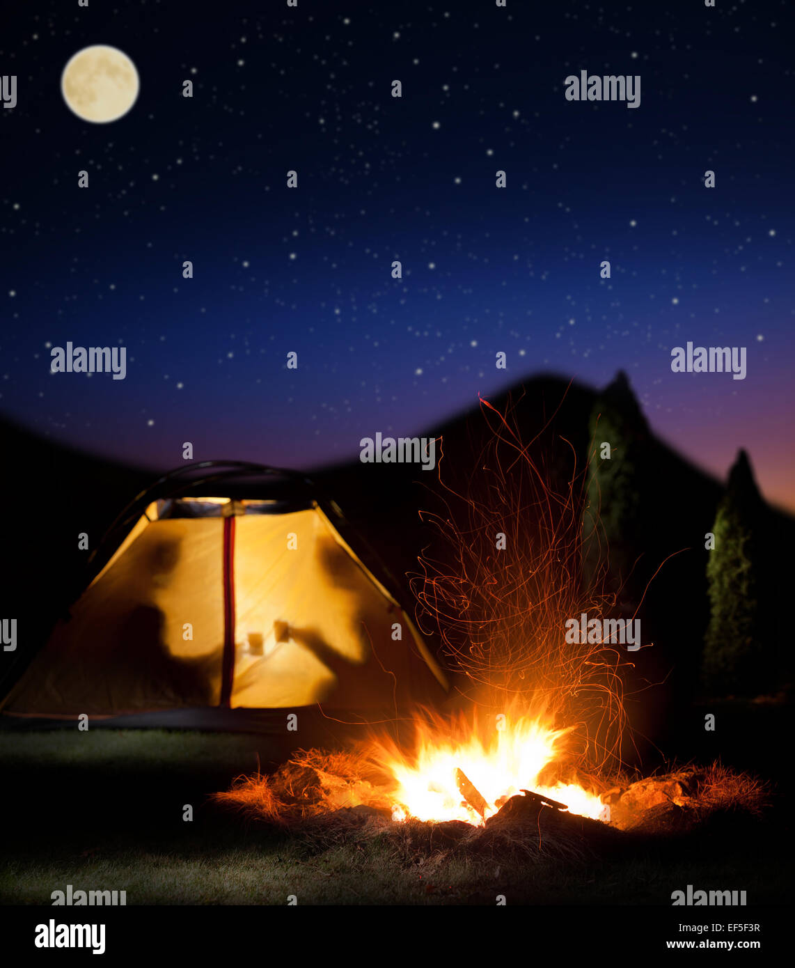 Camp leuchtet in der Nacht. Das Lagerfeuer in der Front als Symbol für Abenteuer und Romantik. Stockfoto