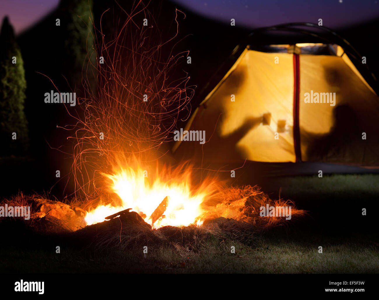 Camp leuchtet in der Nacht. Das Lagerfeuer in der Front als Symbol für Abenteuer und Romantik. Stockfoto
