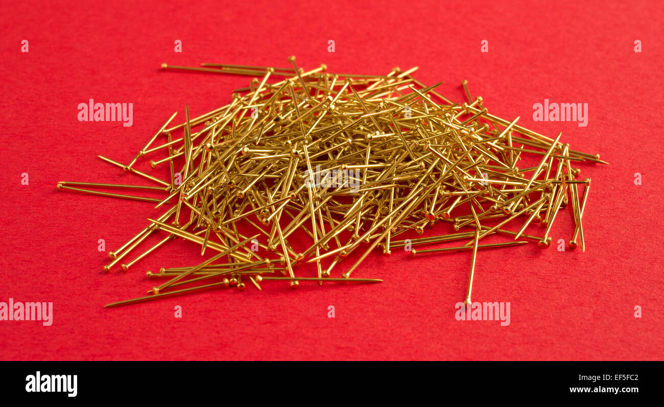 Eine Gruppe von gold Pailletten pins auf einem roten Hintergrund. Stockfoto
