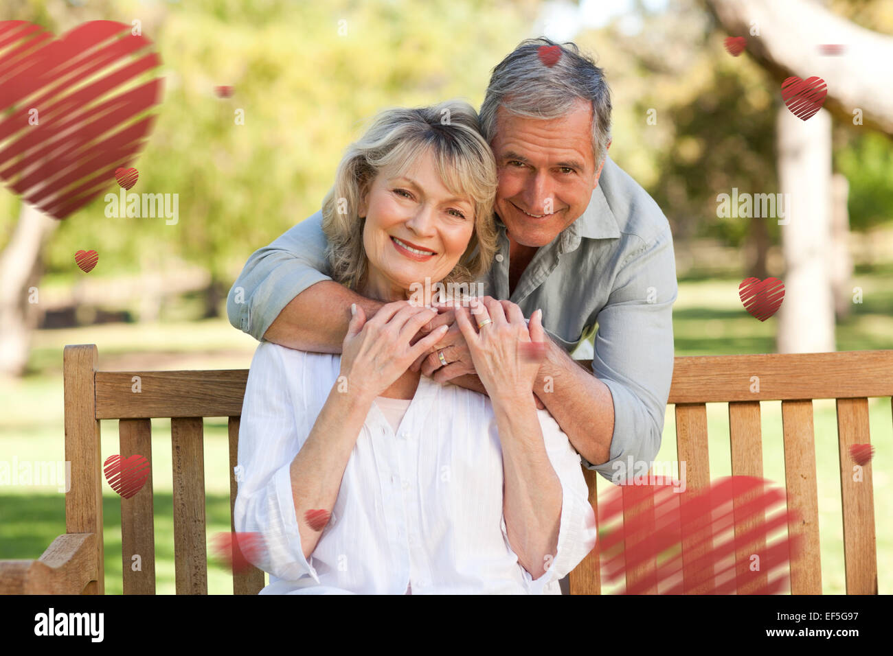 Zusammengesetztes Bild des älteren Menschen umarmt seine Frau, die auf der Bank Stockfoto