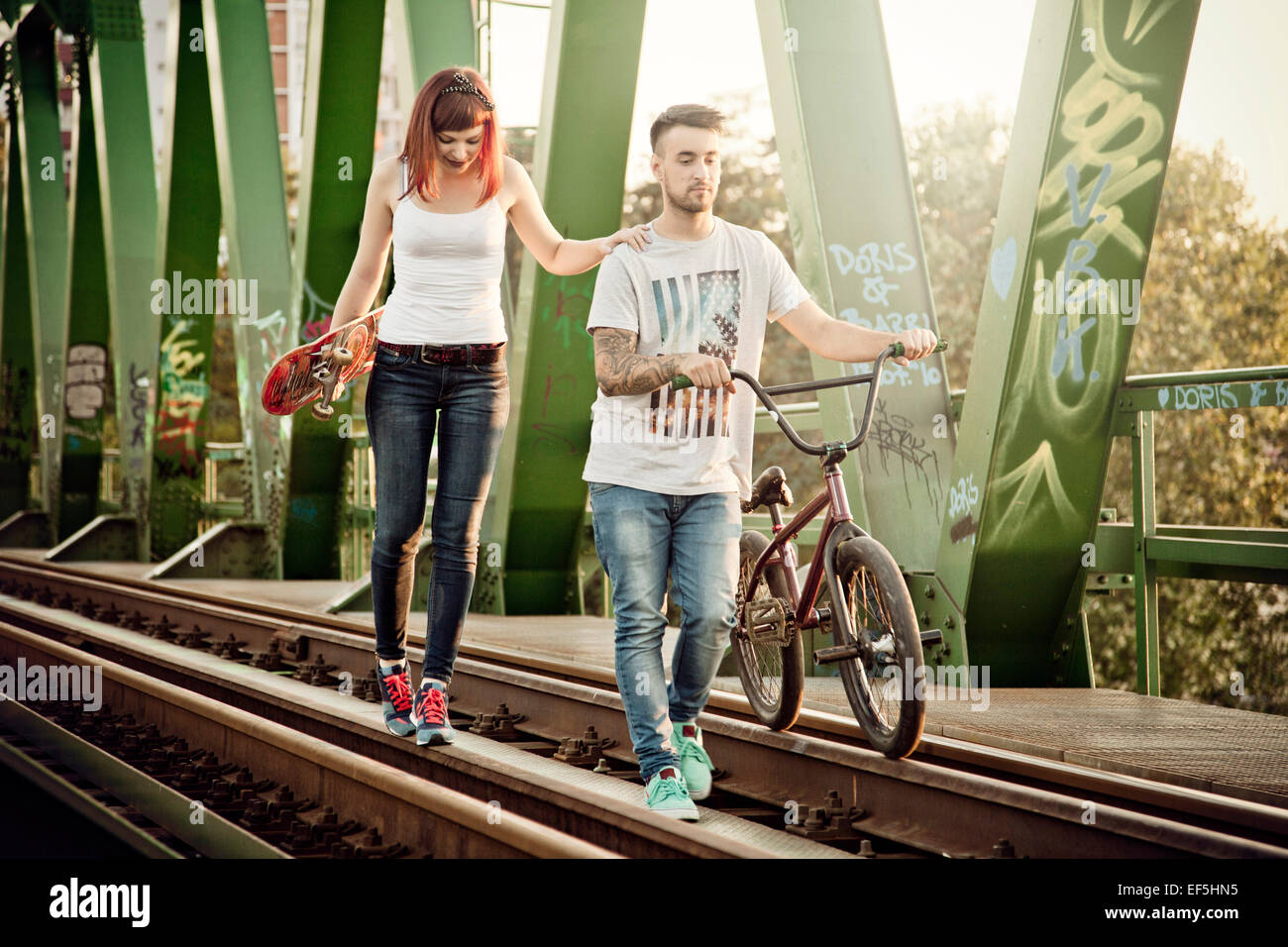 Junges Paar mit Skateboard und BMX Fahrrad im freien Stockfoto