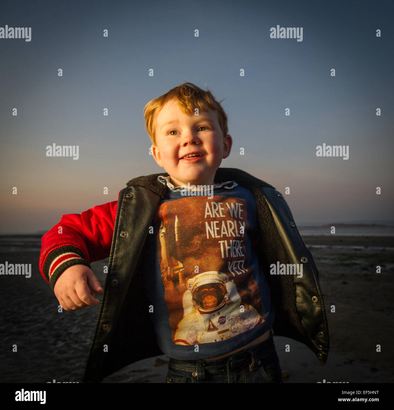 Ein kleiner Junge suchen glücklich am Strand bei Sonnenuntergang UK Westward Ho! Stockfoto