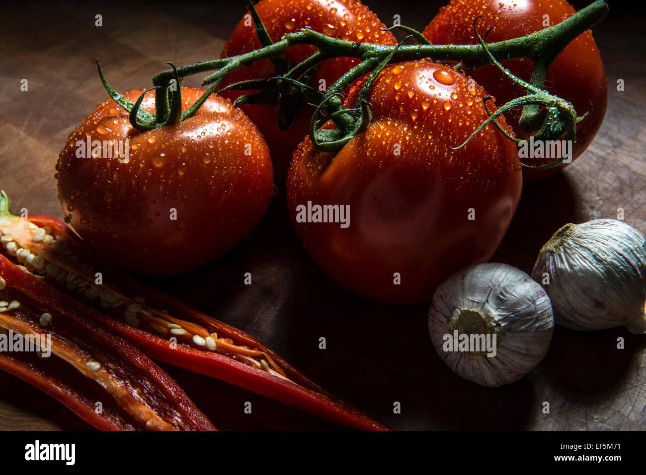 Tomaten, rote Chili und Knoblauch auf einem Schneidebrett Stockfoto