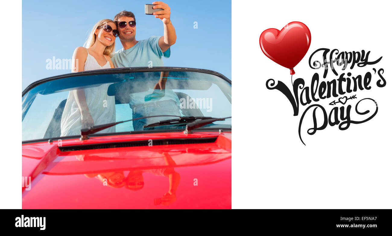 Zusammengesetztes Bild des Lächelns paar stehend im roten Cabriolet unter Bild Stockfoto