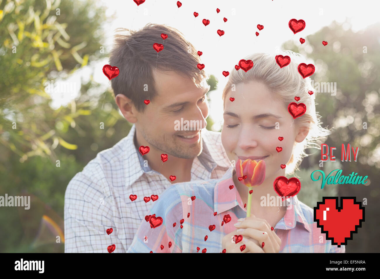 Zusammengesetztes Bild des jungen Paares, die eine Blume im park Stockfoto