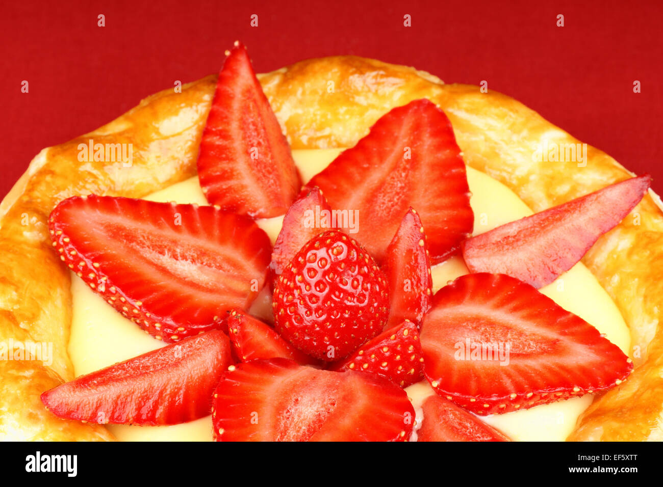 Nahaufnahme einer Erdbeere und Pudding Torte einen roten Hintergrund. Stockfoto