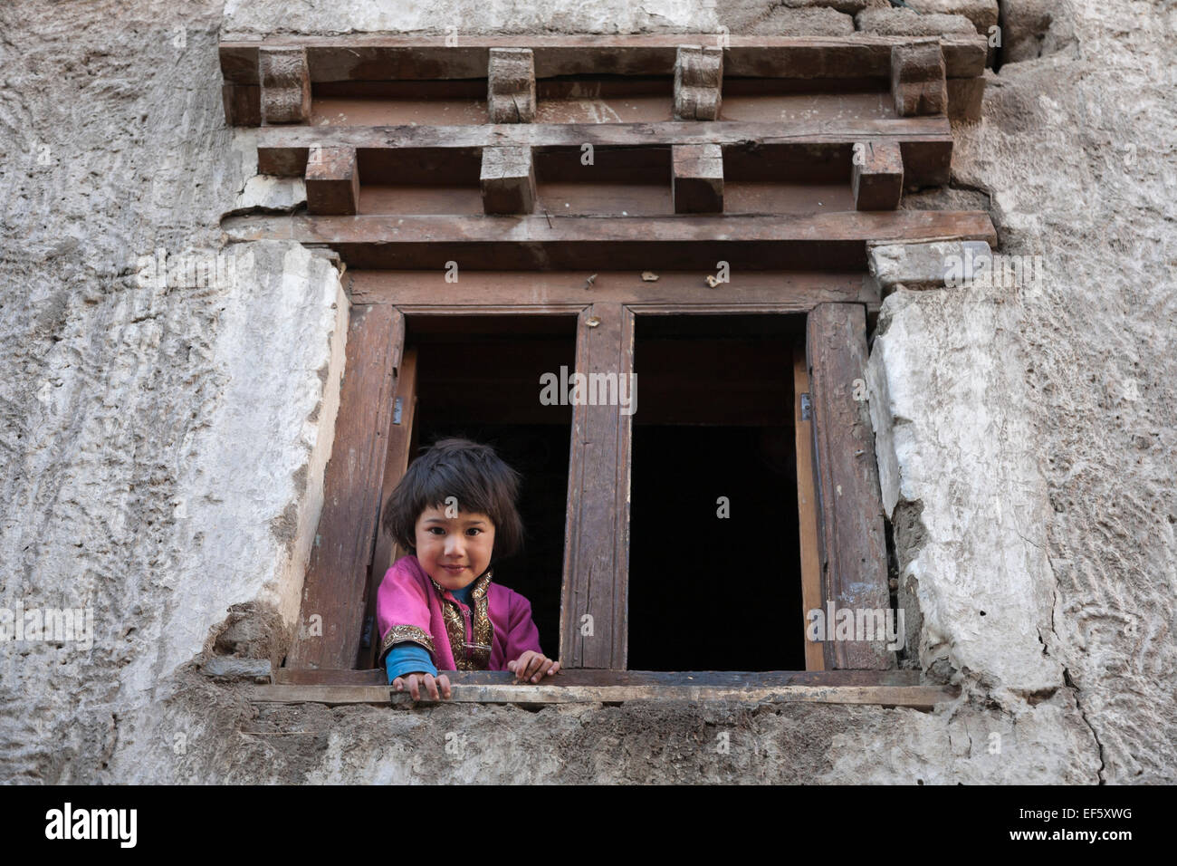 Leh, Ladakh, Indien. Junges Mädchen am Fenster ihres Hauses Stockfoto