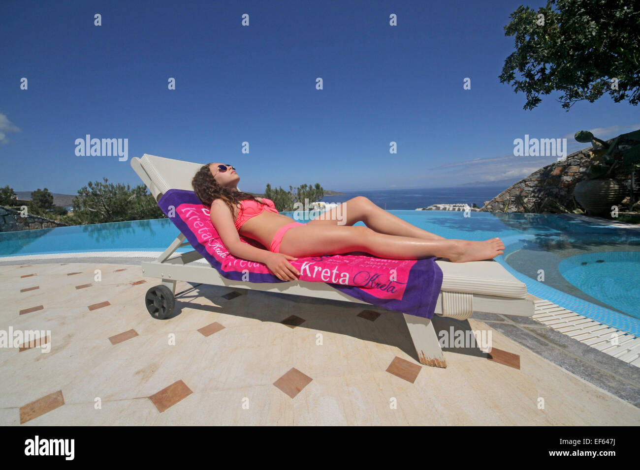 Teenager-Mädchen auf Liegestühlen im INFINITY-Swimmingpool-ELOUNDA-Kreta-Griechenland 5. Mai 2014 Stockfoto