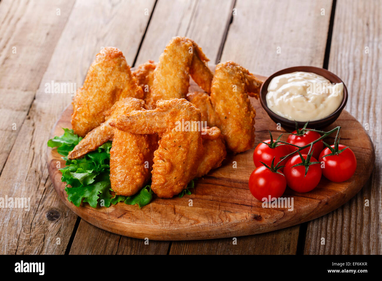 Gebratene Hähnchenflügel mit Sauce und Tomaten Stockfoto